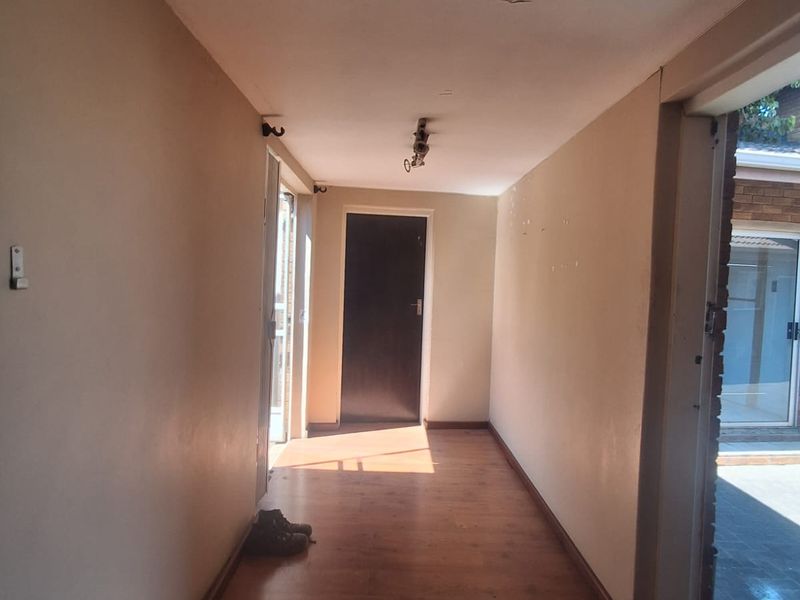 A vacant hallway featuring laminate flooring and neutral wall finishes, providing access to adjacent rooms and outdoor areas.