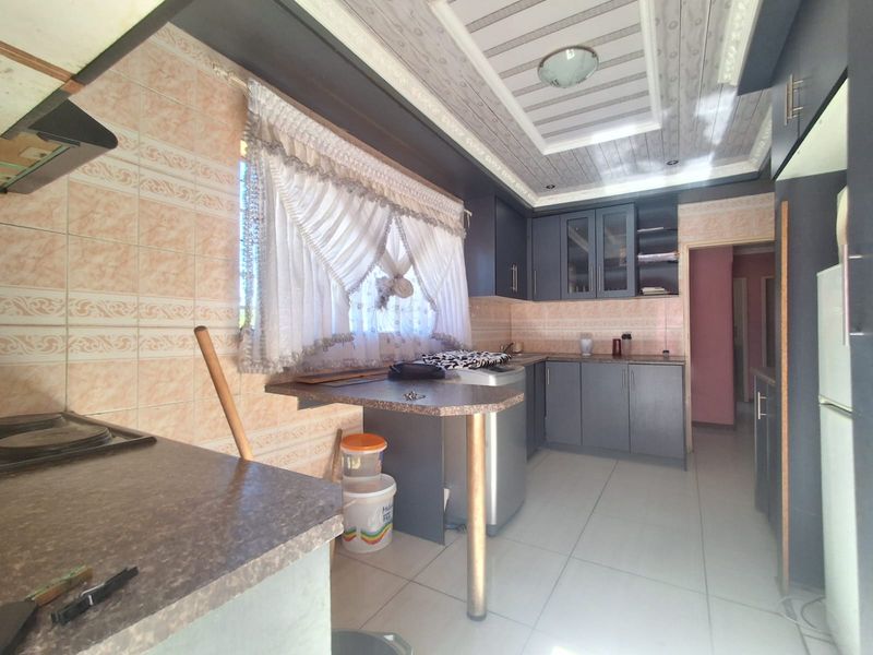 A functional kitchen featuring dark cabinetry, laminate countertops, tiled backsplash, and a drop ceiling with integrated lighting.