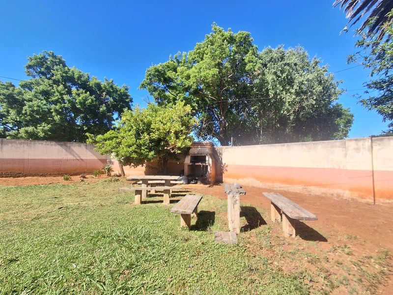 Spacious garden area featuring a built-in braai and perimeter wall, offering potential for outdoor landscaping and entertainment space development.