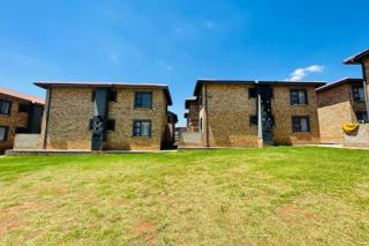 Exterior view of the apartment complex featuring face brick facades and a shared communal lawn area.