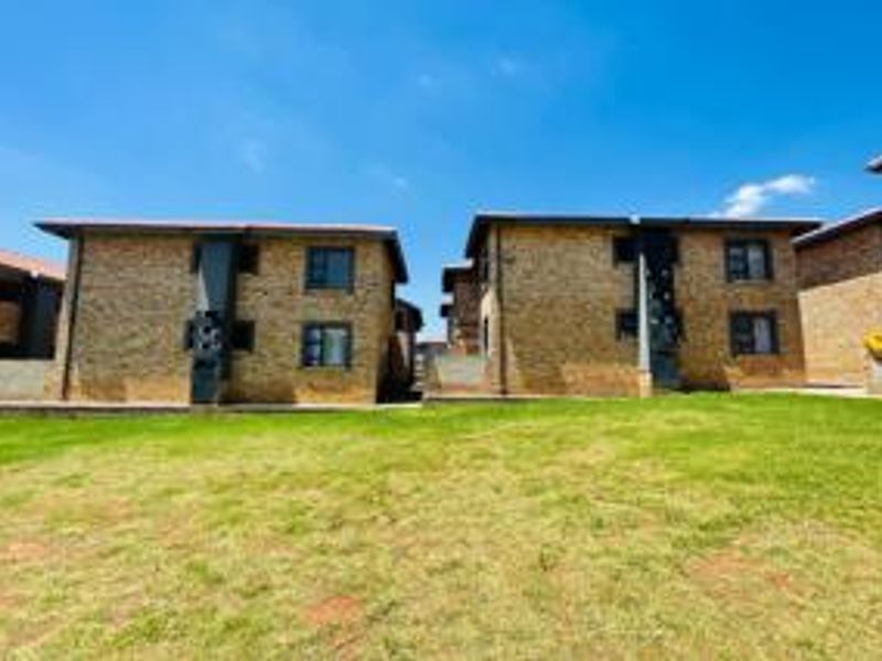 Exterior view of the apartment complex featuring face brick facades and a shared communal lawn area.