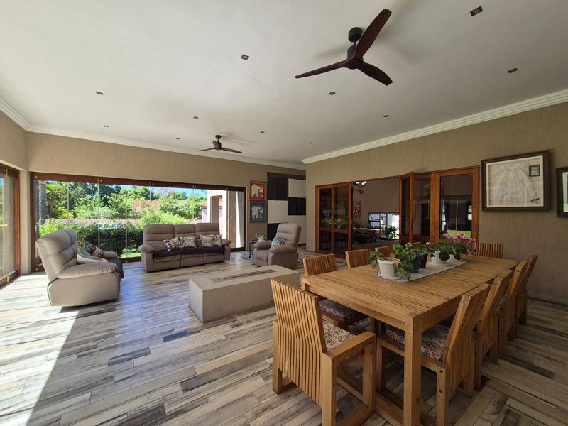 Spacious covered patio featuring tiled flooring, recessed lighting, ceiling fans, and a built-in concrete fire pit, seamlessly connecting to the interior living spaces.