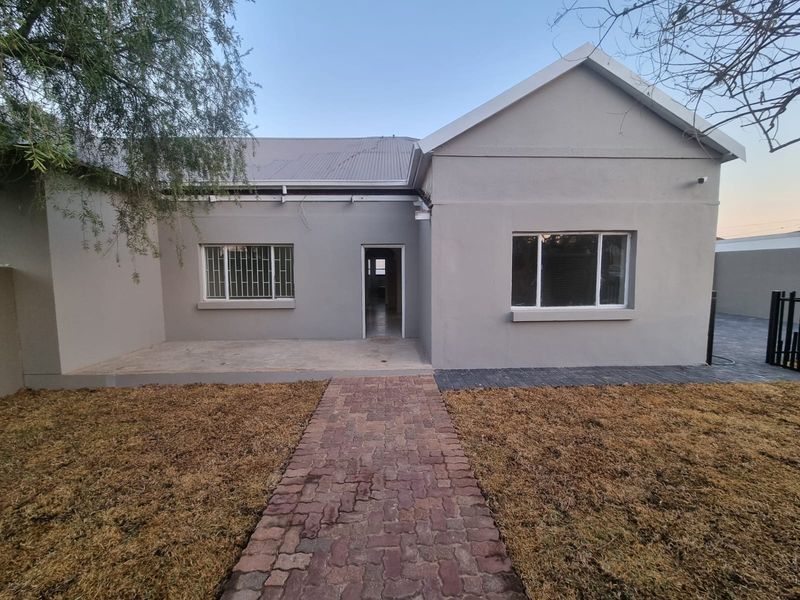 Front view of a single-story house featuring a paved walkway, concrete patio, and neutral exterior paint finish.