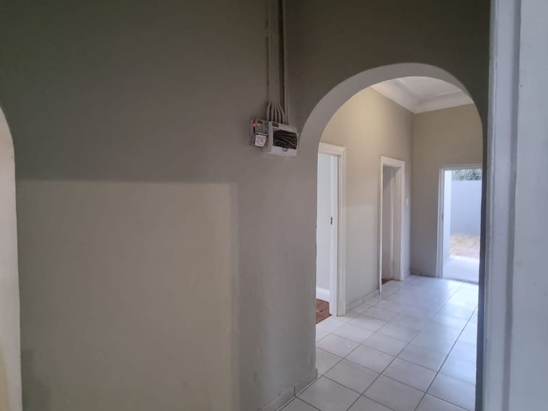 A bright, tiled hallway featuring a classic archway and neutral wall tones, providing a clean and functional transition space within the home.