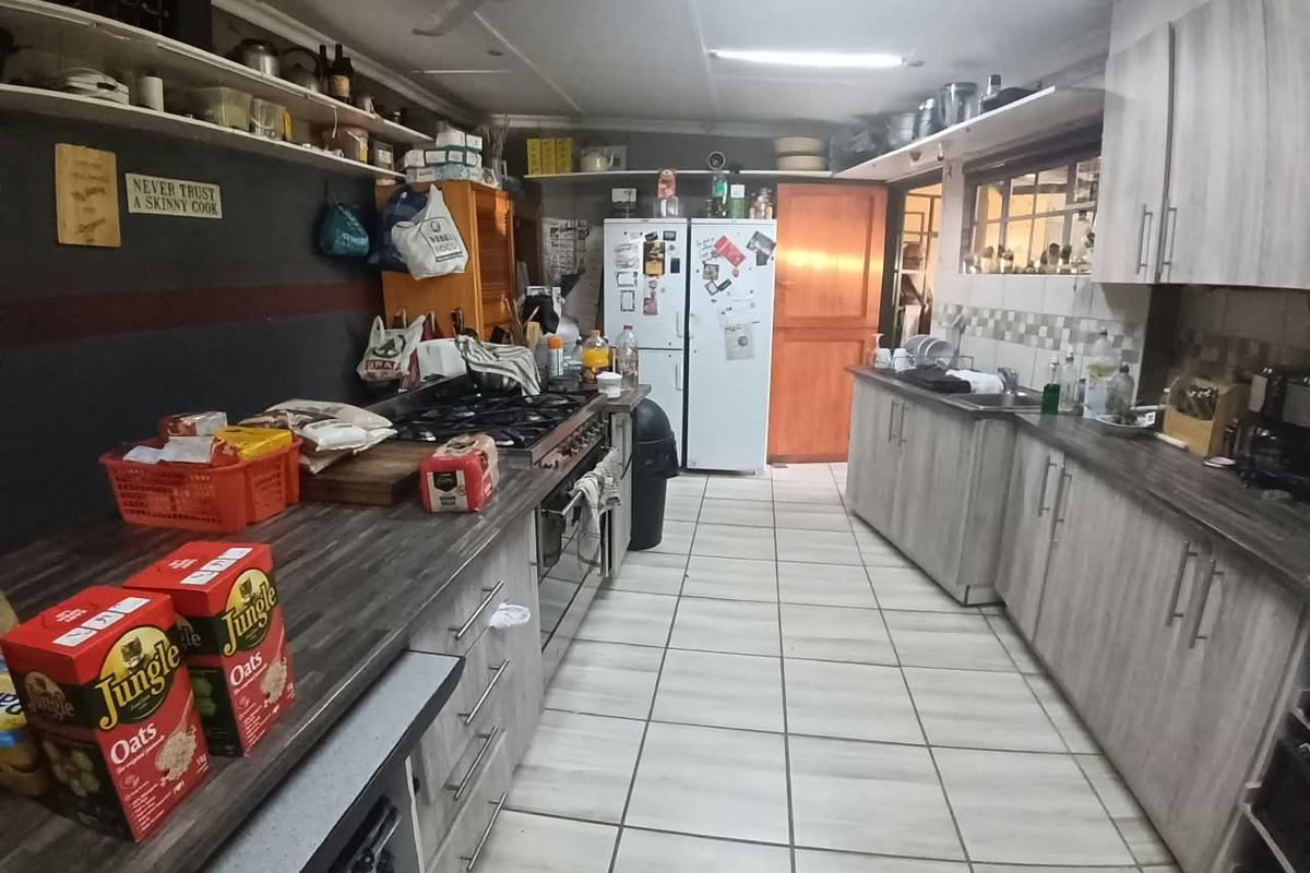 Functional kitchen featuring extensive built-in cabinetry, laminate countertops, gas hob, built-in oven, and tiled flooring, offering a practical layout for daily meal preparation.