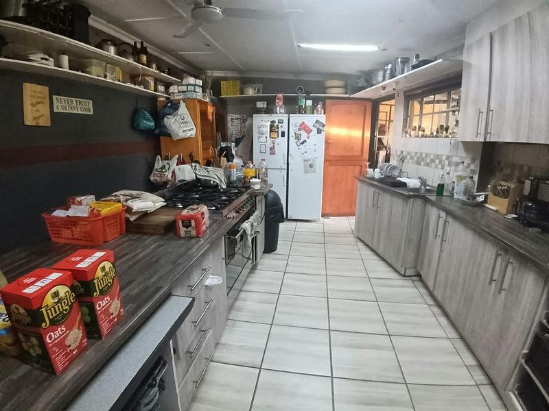 Functional kitchen featuring extensive built-in cabinetry, laminate countertops, gas hob, built-in oven, and tiled flooring, offering a practical layout for daily meal preparation.