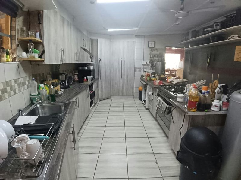 A functional galley-style kitchen featuring light wood-grain cabinetry, tiled flooring, and integrated gas cooking appliances.