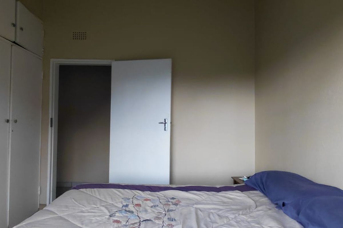 A bedroom featuring built-in cupboards and a ventilation grille, requiring cosmetic updates to improve the overall aesthetic and condition of the space.