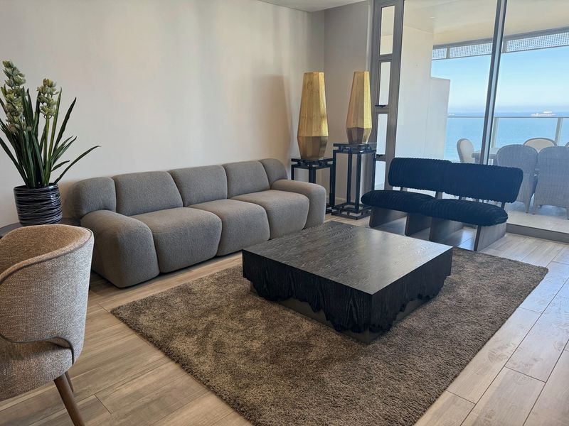 A modern living room featuring large sliding glass doors that provide natural light and access to a balcony with ocean views.