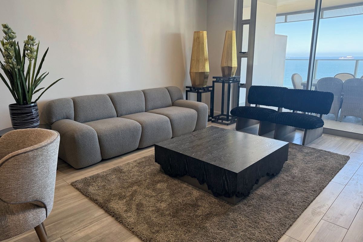 A modern living room featuring large sliding glass doors that provide natural light and access to a balcony with ocean views.