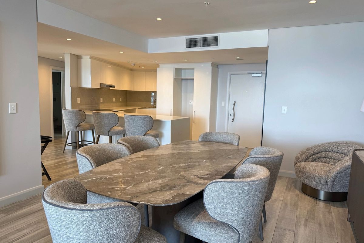 Modern open-plan living and dining area featuring a sleek kitchen with stone island, recessed lighting, and high-quality laminate flooring throughout.