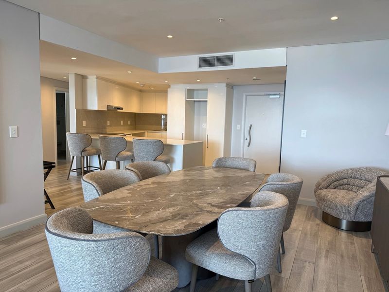 Modern open-plan living and dining area featuring a sleek kitchen with stone island, recessed lighting, and high-quality laminate flooring throughout.