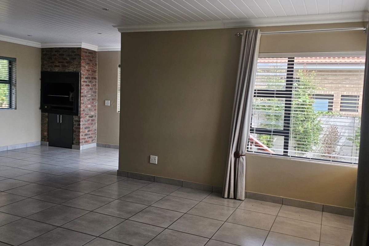 Spacious living area featuring tiled flooring, a built-in brick fireplace, and a classic tongue and groove ceiling, offering a versatile blank canvas.