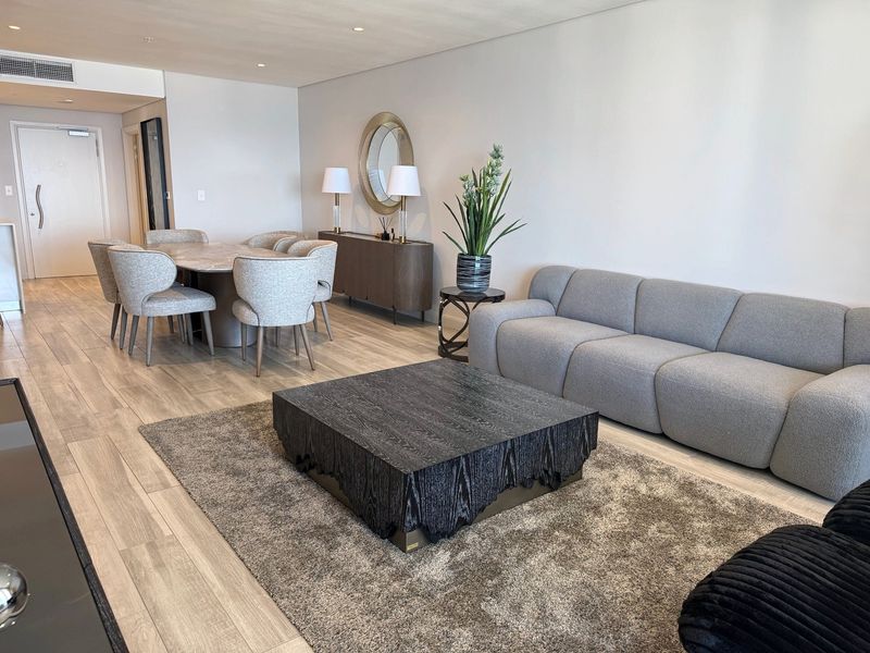 A spacious open-plan living and dining area featuring modern wood-look tile flooring, recessed ceiling lighting, and integrated ducted air conditioning.