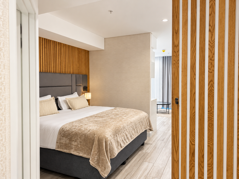 A modern, well-appointed bedroom featuring stylish timber slat wall paneling, neutral tones, and high-quality finishes, creating a warm and inviting atmosphere.