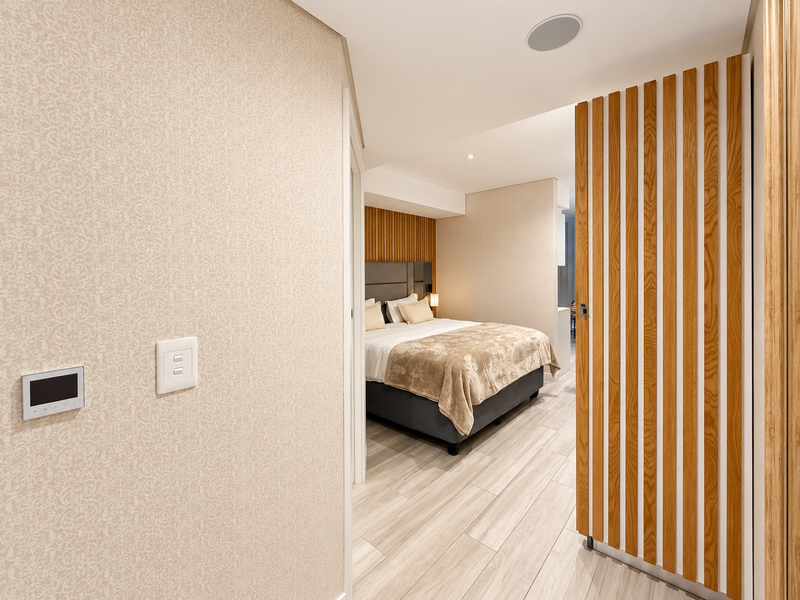 Modern bedroom featuring a stylish timber slat feature wall, tiled flooring, and integrated smart home controls, offering a clean and contemporary living space.
