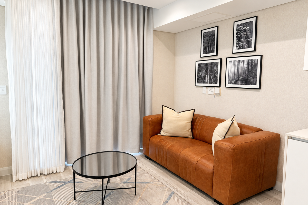 A modern, well-maintained living area featuring neutral wall finishes, tiled flooring, recessed ceiling lighting, and floor-to-ceiling curtains providing access to natural light.