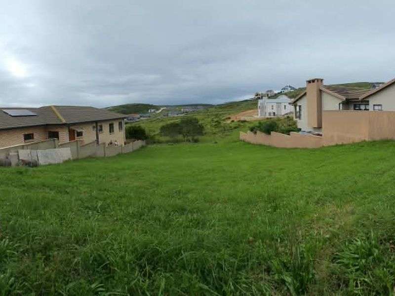 A vacant residential plot featuring grassed land enclosed by brick boundary walls, situated within a developed neighborhood.
