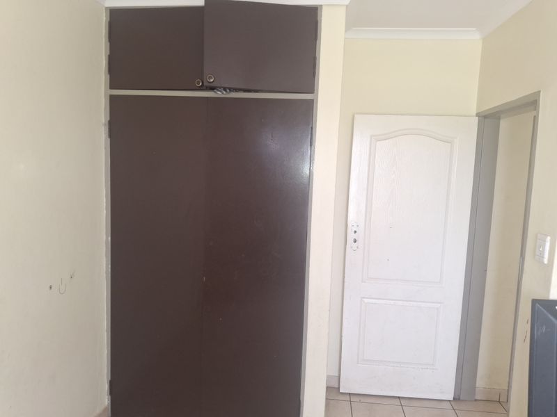 A bedroom featuring a built-in cupboard with overhead storage, tiled flooring, and standard interior finishes, presenting a blank canvas for potential updates.