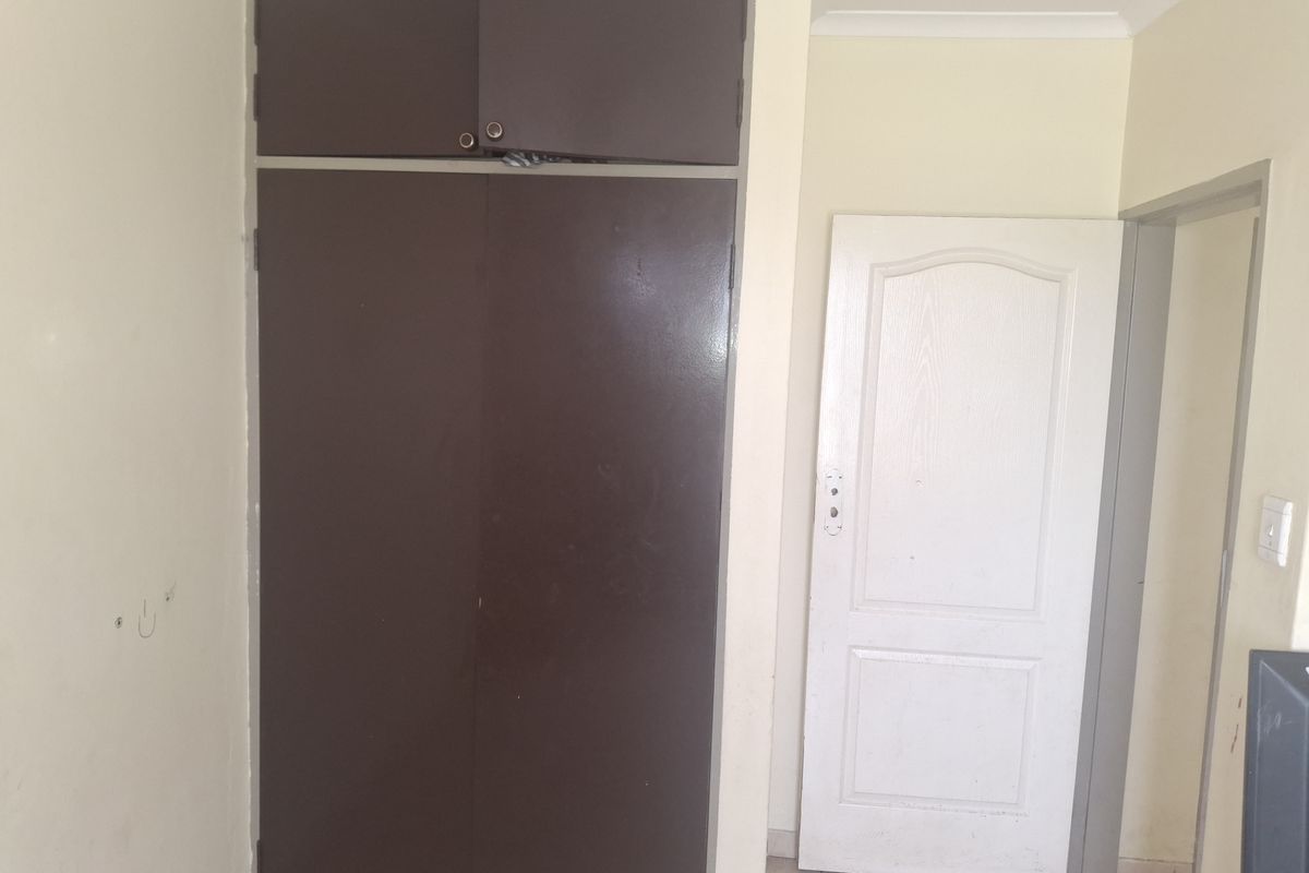A bedroom featuring a built-in cupboard with overhead storage, tiled flooring, and standard interior finishes, presenting a blank canvas for potential updates.