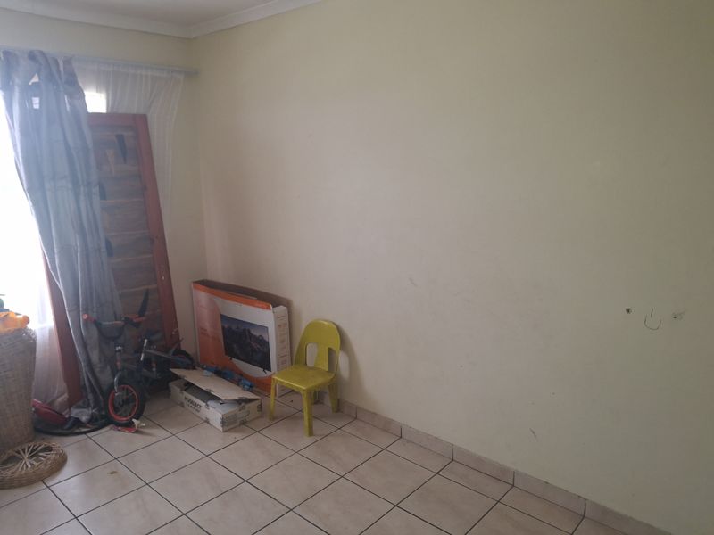 A sparsely furnished living area featuring tiled flooring and neutral walls, offering a blank canvas for potential interior design updates.