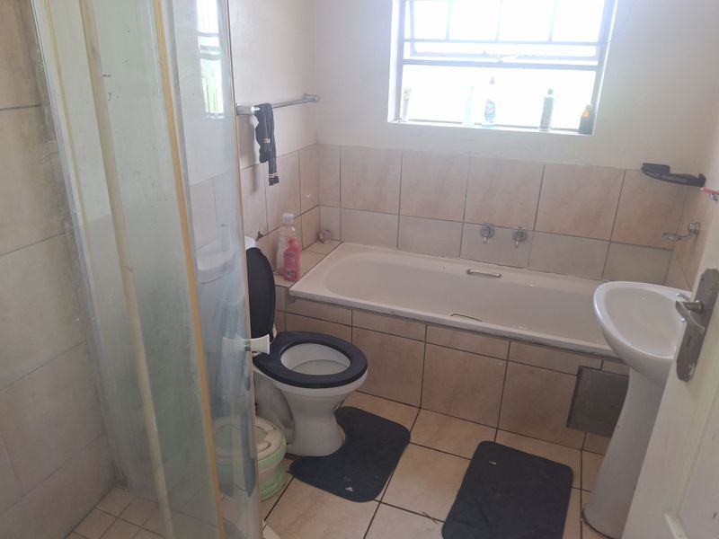 A functional bathroom featuring a bathtub, pedestal basin, toilet, and a separate shower enclosure with tiled finishes throughout.