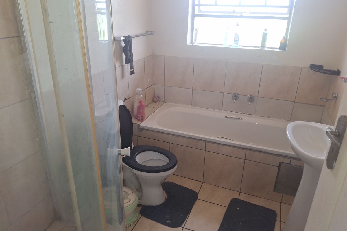 A functional bathroom featuring a bathtub, pedestal basin, toilet, and a separate shower enclosure with tiled finishes throughout.