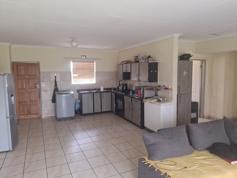 Open plan living and kitchen area featuring tiled flooring, built-in cabinetry, and a functional layout with direct access to the entrance.