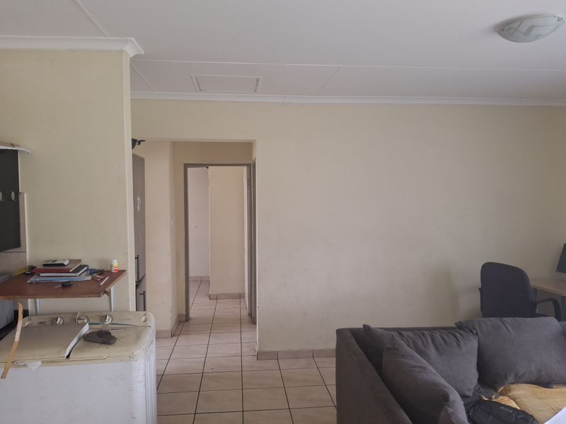 An open-plan living area featuring tiled flooring and neutral wall finishes, providing a functional layout with direct access to the hallway.