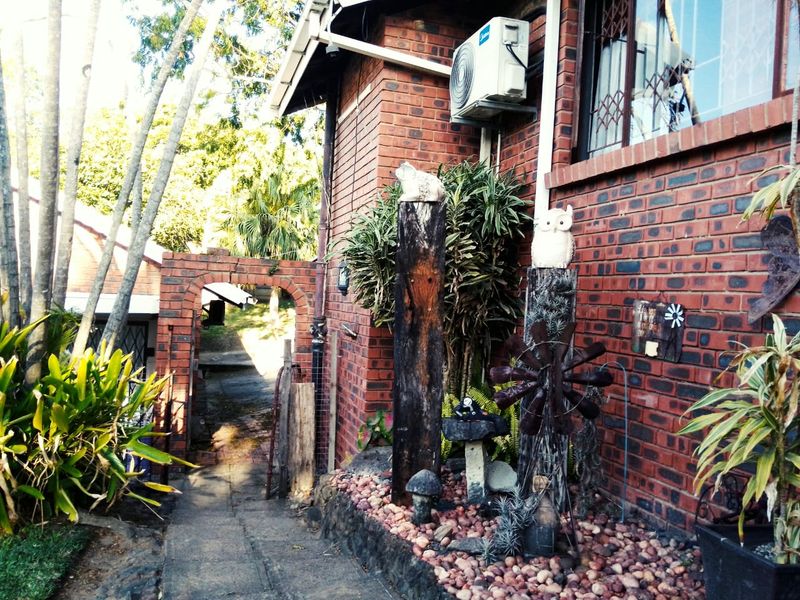 A side view of the brick exterior featuring a paved pathway, a brick archway, and an installed air conditioning unit.