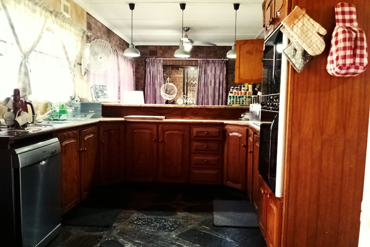 A traditional kitchen featuring warm wooden cabinetry, a double wall oven, stone flooring, and a brick feature wall with breakfast bar pass-through.