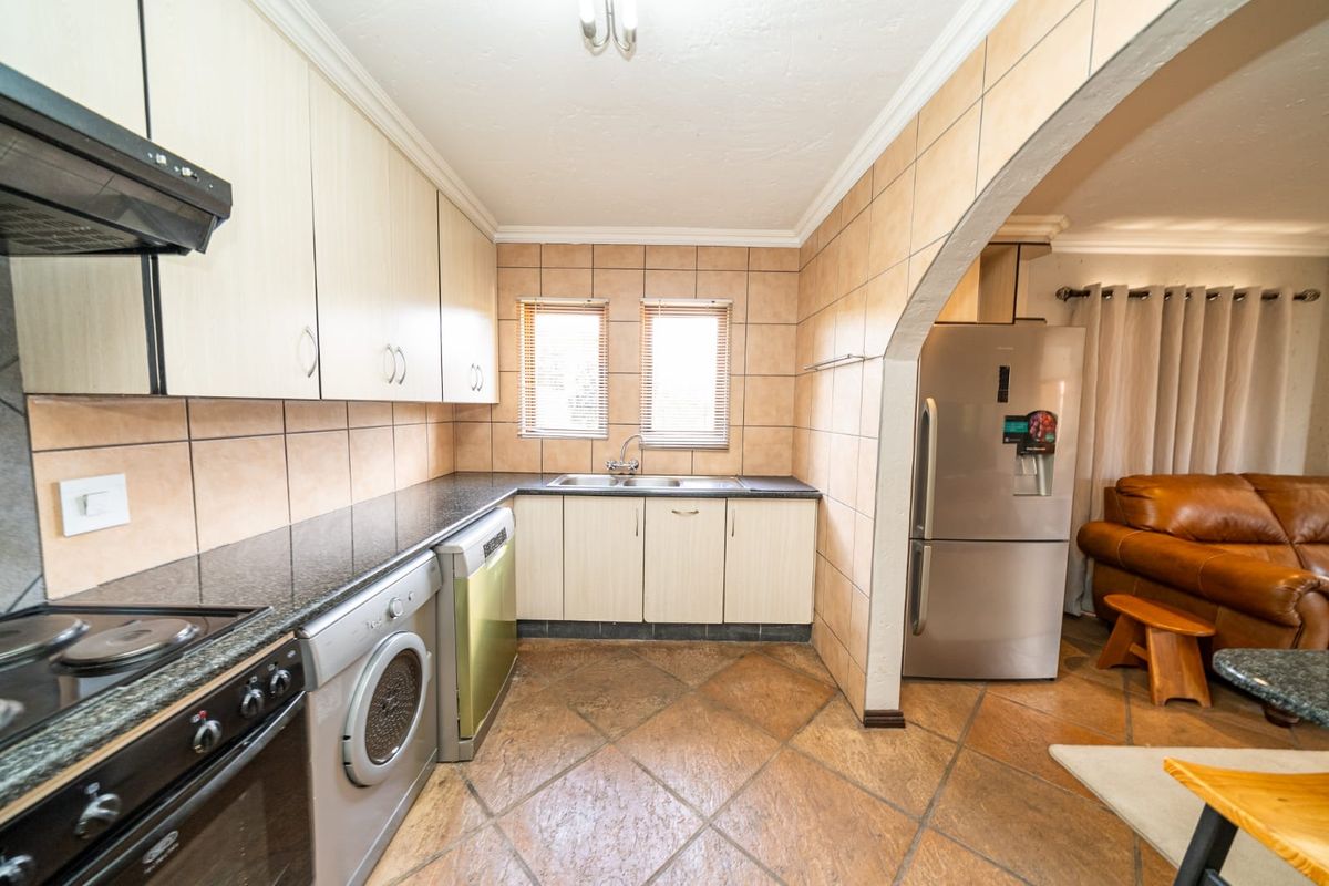 A functional kitchen featuring granite countertops, built-in cabinetry, tiled backsplash, and ceramic flooring, with an open-plan layout connecting to the adjacent living area.