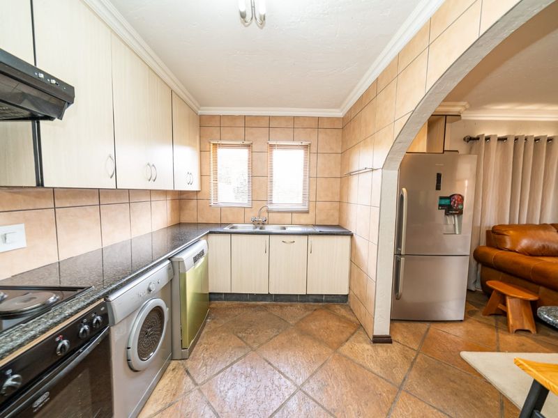 A functional kitchen featuring granite countertops, built-in cabinetry, tiled backsplash, and ceramic flooring, with an open-plan layout connecting to the adjacent living area.