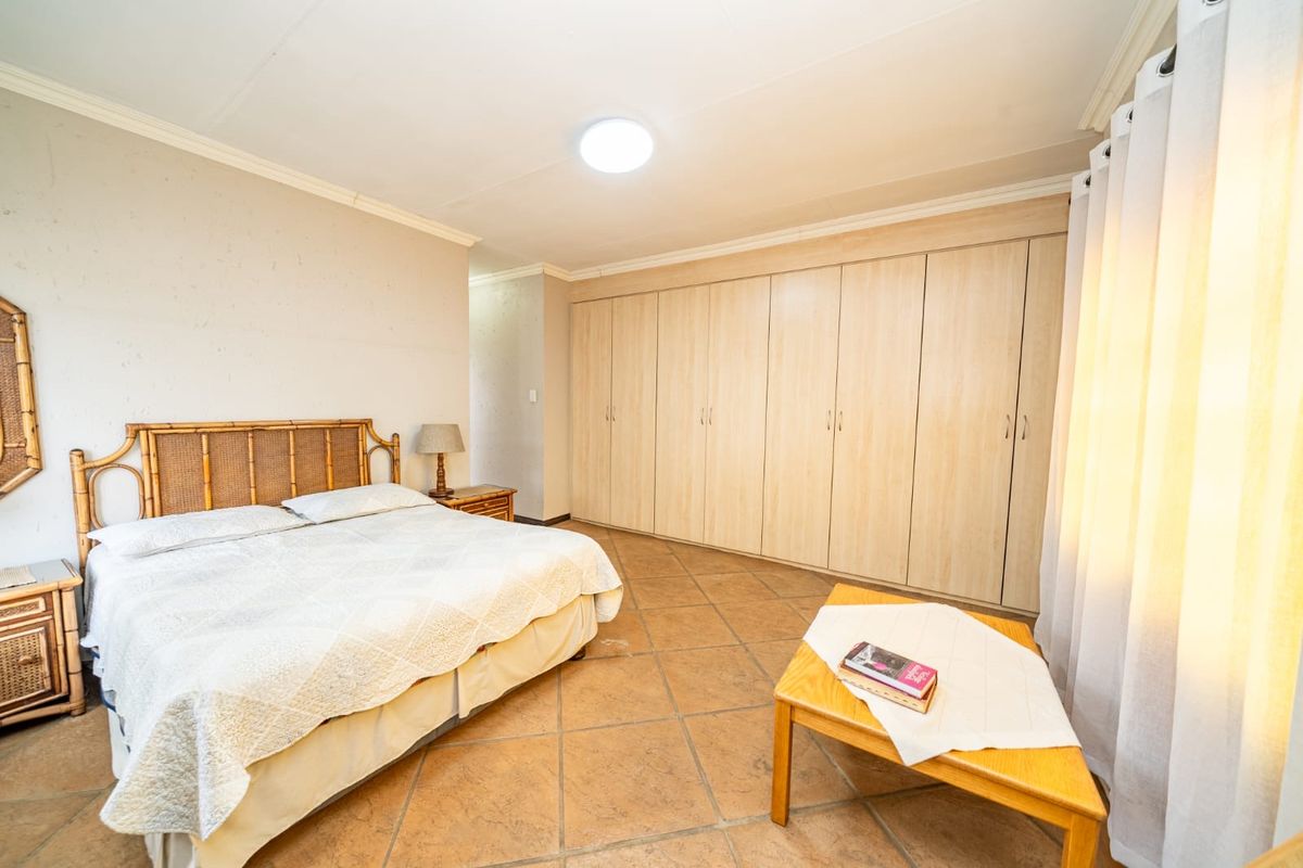 Spacious bedroom featuring extensive built-in cupboards, tiled flooring, and neutral wall finishes, offering a functional and well-maintained living space.