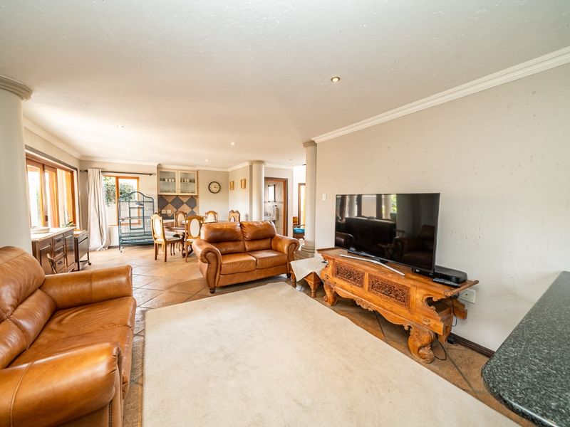 Spacious open-plan living and dining area featuring tiled flooring, decorative columns, and recessed lighting, creating a comfortable and functional family space.