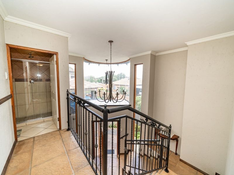 A spacious landing area featuring tiled flooring, a wrought iron staircase railing, and direct access to an adjacent shower room.