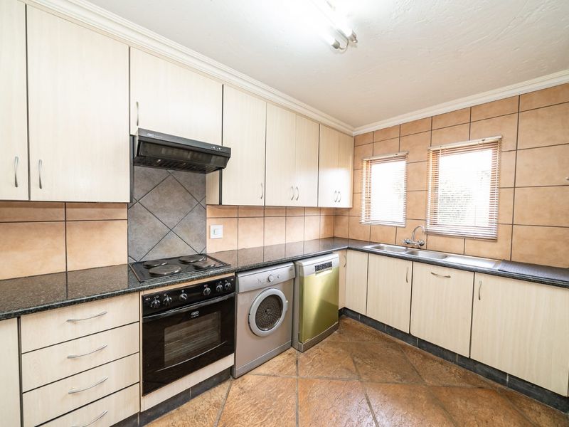 Functional kitchen featuring light wood cabinetry, granite countertops, tiled backsplash, and integrated appliances including an oven, hob, and double sink.