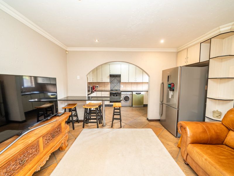 Open-plan living area featuring a breakfast bar and an arched transition into the kitchen, complete with tiled flooring and built-in cabinetry.