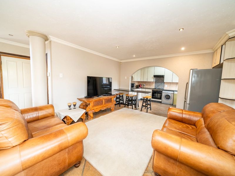 Open-plan living area featuring a kitchen with breakfast bar, arched transition, tiled flooring, and recessed lighting, creating a functional and connected living space.