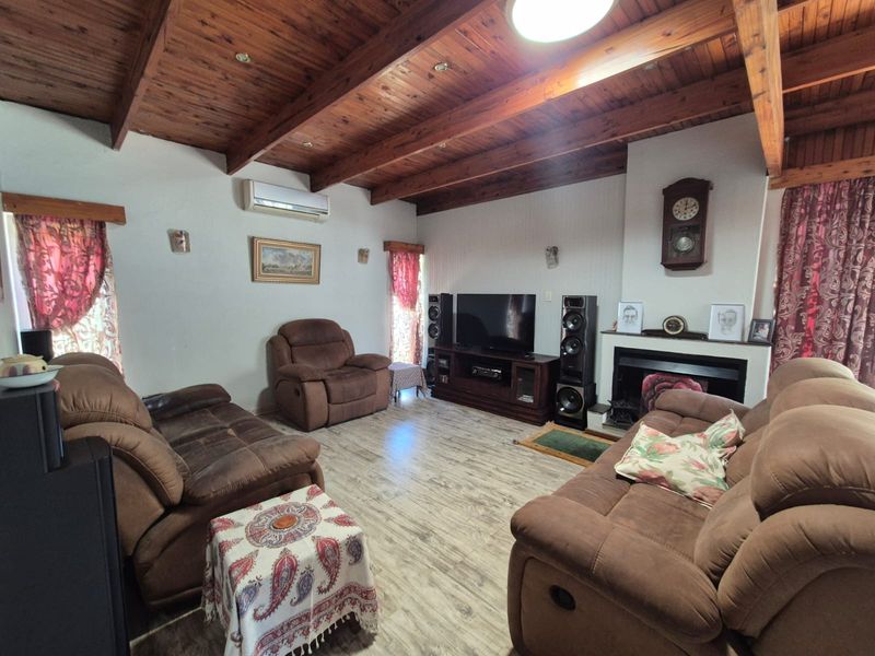 Spacious living room featuring exposed timber ceiling beams, a fireplace, and split-system air conditioning, finished with durable laminate flooring.