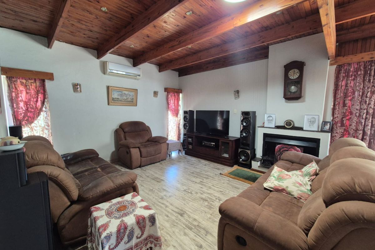 Spacious living room featuring exposed timber ceiling beams, a fireplace, and split-system air conditioning, finished with durable laminate flooring.