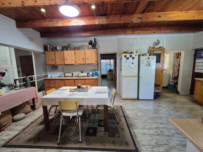 Spacious kitchen featuring timber beam ceilings, wooden cabinetry, and tiled splashbacks, offering a functional layout with an adjacent scullery area.