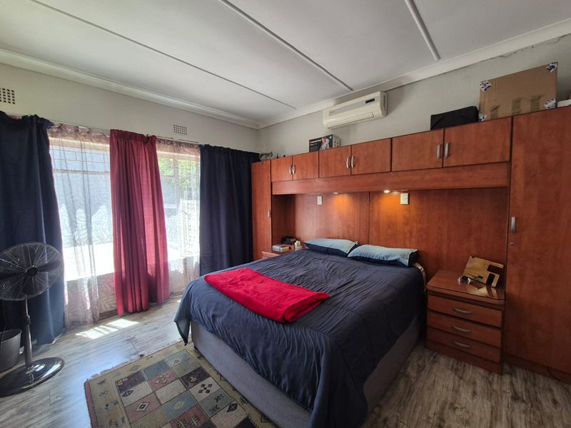 A bedroom featuring built-in wooden cabinetry, an integrated air conditioning unit, and laminate flooring.