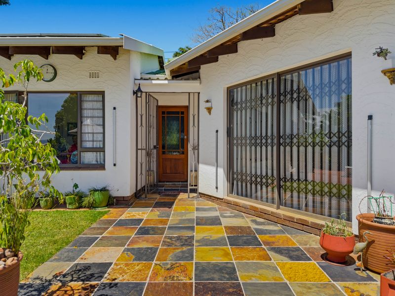 Front entrance area featuring a slate tiled patio, timber front door, and sliding glass doors with security gates.