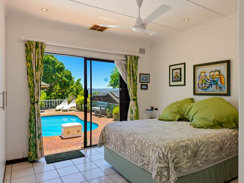 Bright bedroom featuring tiled flooring, a ceiling fan, and large sliding glass doors providing direct access to the outdoor pool area.