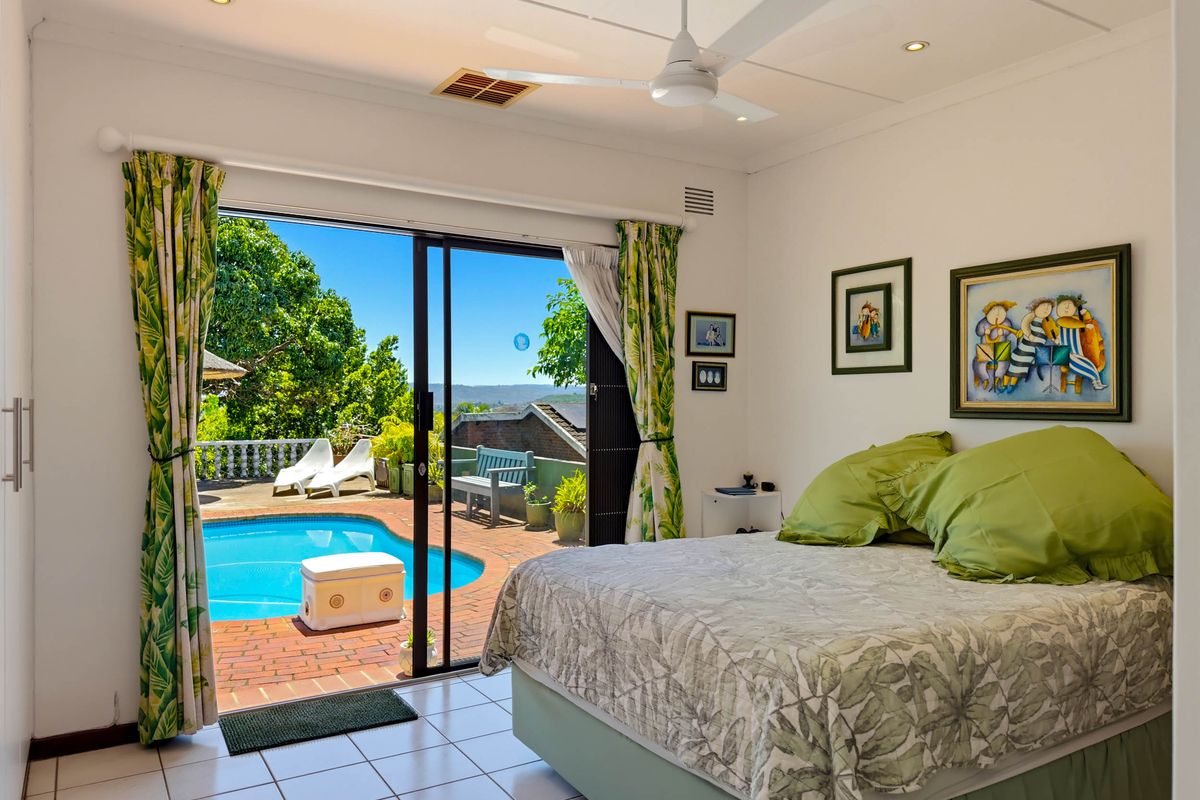 Bright bedroom featuring tiled flooring, a ceiling fan, and large sliding glass doors providing direct access to the outdoor pool area.