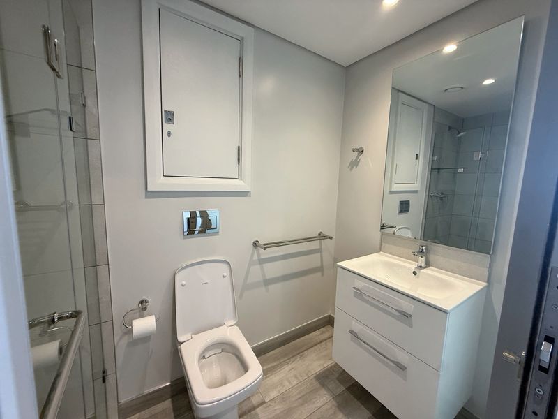 Modern bathroom featuring a wall-hung toilet, vanity cabinet with integrated basin, and a glass shower enclosure with contemporary finishes.