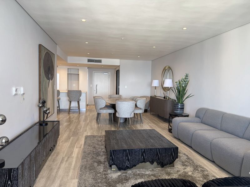 A spacious open-plan living and dining area featuring modern laminate flooring, recessed lighting, and a seamless transition to the kitchen breakfast bar.