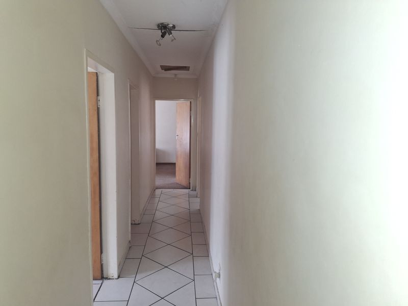 A functional hallway featuring tiled flooring and a ceiling access hatch, connecting multiple rooms within the property.