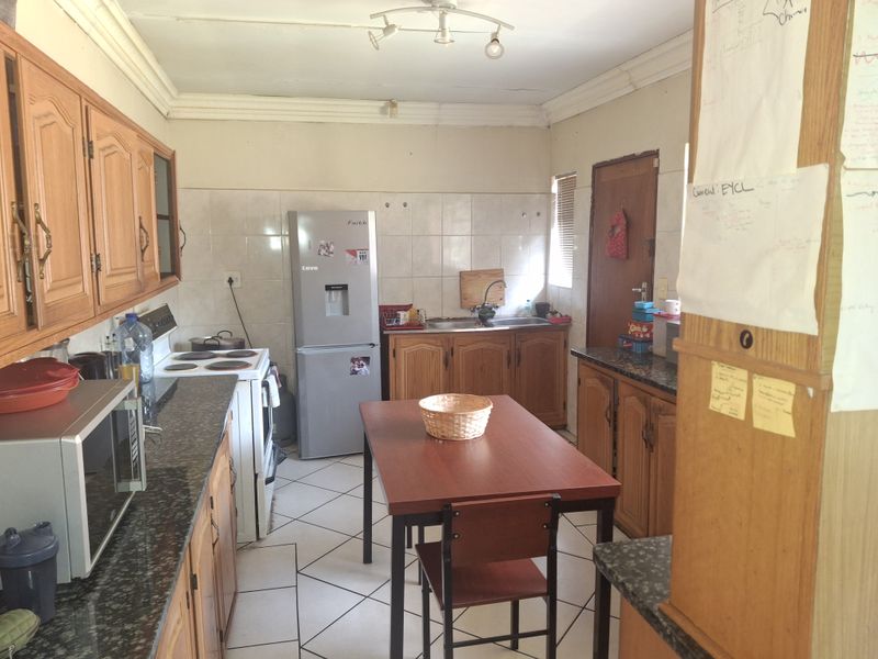 A functional kitchen featuring wooden cabinetry, granite countertops, tiled splashbacks, and tiled flooring, offering a practical layout with potential for modern updates.